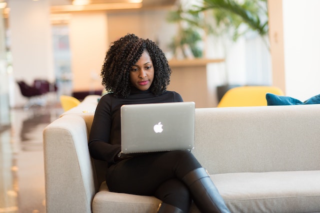 a landlord with tight natural curls sits on a white couch while posting rental listings on numerous websites